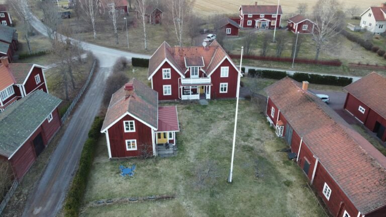 Aerial view of traditional red wooden houses in rural Dalarnas län, Sweden, during fall.