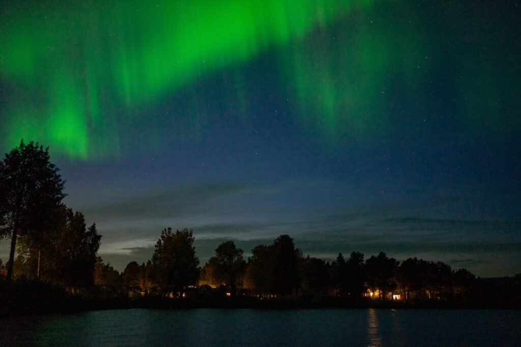 Stunning Northern Lights over serene rural landscape in Kiruna, Sweden, illuminating the night sky.