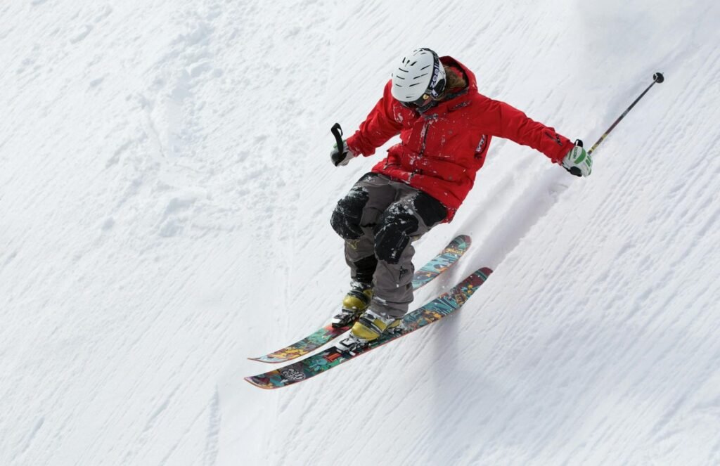 A skier in a red jacket descends a steep snowy slope, showcasing skill and adventure in winter